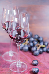 Fresh grape and red wine on the vintage table with two glasses, selective focus