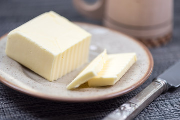 Piece of butter on plate with knife. Background and shallow focus.