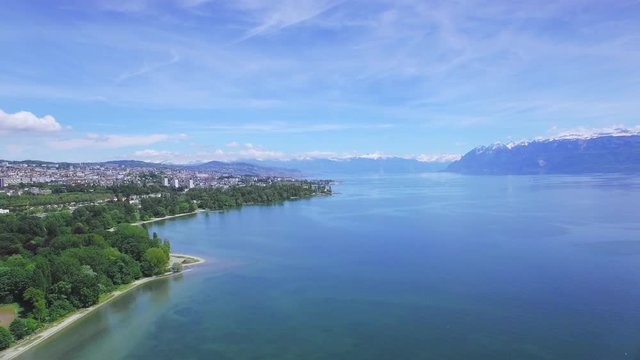 Lausanne Lake Geneva aerial drone shot. Flying along the lake shore - with the city of Lausanne and the Alps in the background