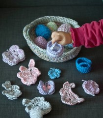 Easter decoration, bunny rabbits, butterflies, eggs, baskets, made of crochet colorful yarn on wooden texture background. Homemade decor. Top view, shallow depth of focus. Easter holidays.