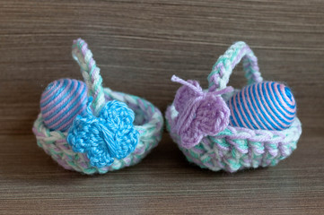 Fototapeta na wymiar Easter decoration, crochet mini basket, striped colorful egg wrapped in soft yarn thread, pastel colors, butterfly, wooden texture background. Homemade decor. Shallow depth of focus. Easter holidays.