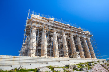 Restoration work in progress at world heritage ancient Parthenon with machine crane, scaffolding and blue sky background, Athens, Greece