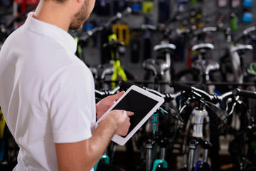 cropped shot of young man using digital tablet with blank screen in bicycle shop