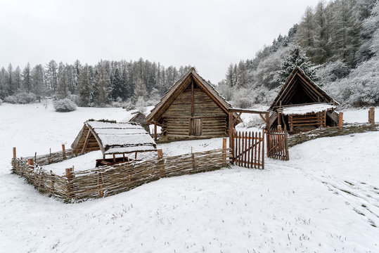 Snow covered reconstructed Celtic settlement at Havranok in the Liptov region of Slovakia showing wooden houses, fences and early historical architecture in winter