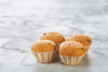 Tasty muffins arranged in pattern on light textured background, close-up, shallow depth of field, selective focus.