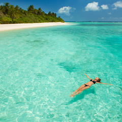 Woman swim and relax in the sea. Happy island lifestyle. White sand, crystal-blue sea of tropical beach. Vacation at Paradise. Ocean beach relax, travel to Maldives islands