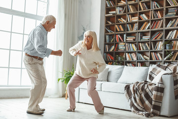 Senior couple together at home retirement concept dancing active dance playful