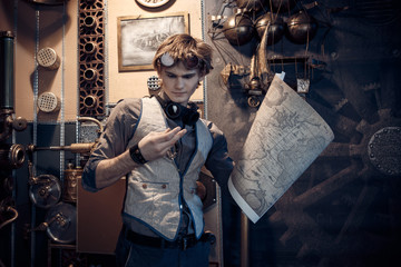 Portrait of a young mad scientist traveler in a steampunk style suit with a card.