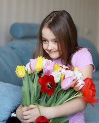 Pretty little shy girl holding big bouquet of tulips