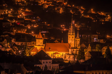 Fototapeta na wymiar Night view from above on the city and an old building with towers. Romania. Brasov. Transylvania. Europe. 