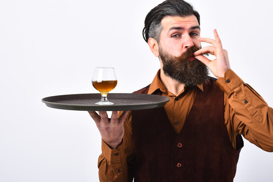 Man with beard holds glass with alcohol on white background.