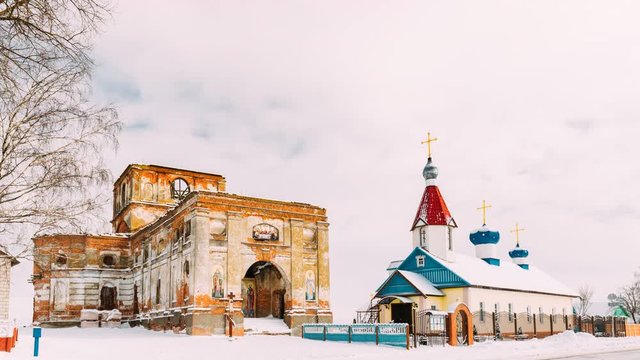 Village Lenino, Dobrush District, Gomel Region, Belarus. Time Lapse Timelapse Time-lapse Of Old Ruined Orthodox Church Of The St. Nicholas Near New Church In Winter Day. Historical Heritage