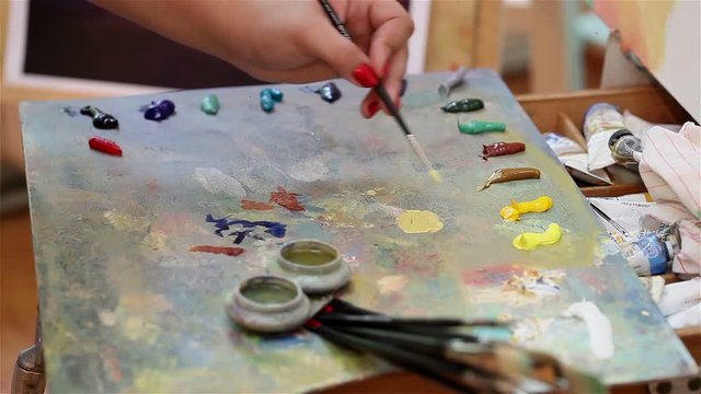 Artist mixes paint on the palette, Art brush mixed paint on the palette, artist brush mix color oil painting on palette, artistic brush, hand close-up