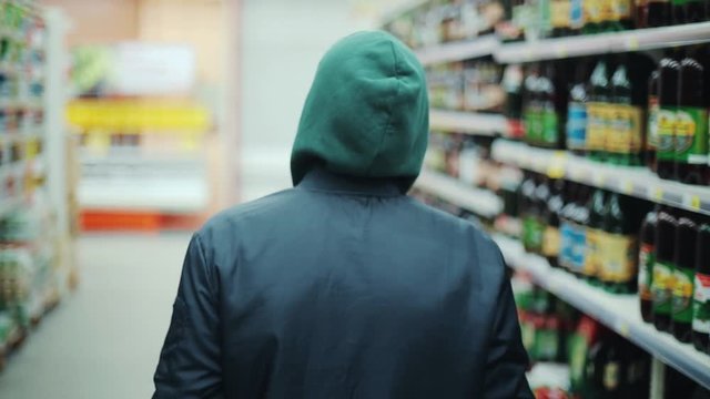 Portrait man steals bottle of alcohol in supermarket go away shot behind shoplifting larceny technology crime store theft criminal customer illegal retail poor looting lifting security shop consumer