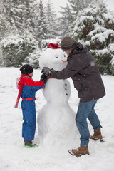 Vater und Sohn mit dem gemeinsam gebauten Schneemann