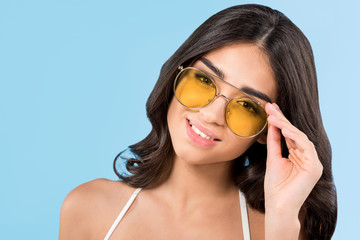 beautiful smiling girl posing yellow sunglasses, isolated on blue