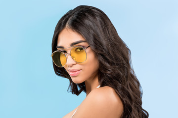 attractive girl posing in yellow sunglasses, isolated on blue