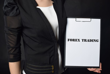 In the hands of a businessman a notebook with the inscription:FOREX TRADING