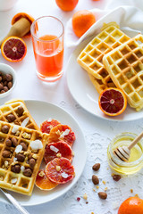 Healthy breakfast. Belgian waffles with nuts and sicilian oranges on the white table