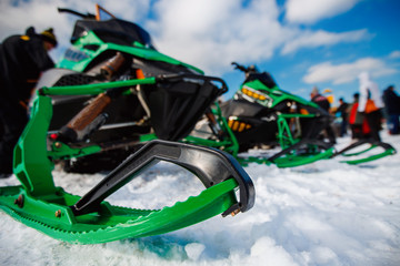Snowmobile. Close-up of row of snowmobiles stand in snow, view from below, skiing.