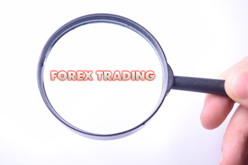 Businessman looking at a magnifying glass word:FOREX TRADING