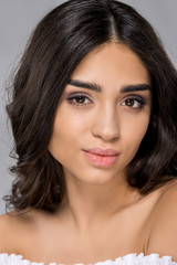 Obraz premium portrait of brunette tanned girl looking at camera, isolated on grey