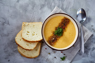 Porcelain bowl of pumpkin soup on napkin over white textured background, close-up, selective focus, top view.