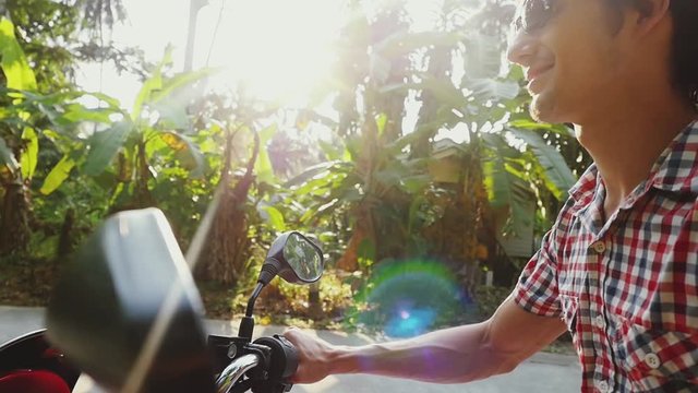 Young happy man traveler in sunglasses driving motorbike on tropical sunny road. slow motion. lens flare effects. 1920x1080