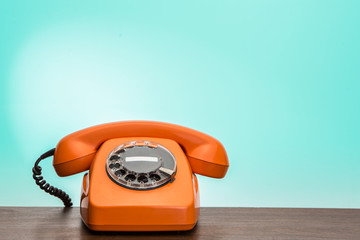 Classic orange phone on desk.