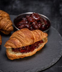 baked croissant with strawberry jam on a black background