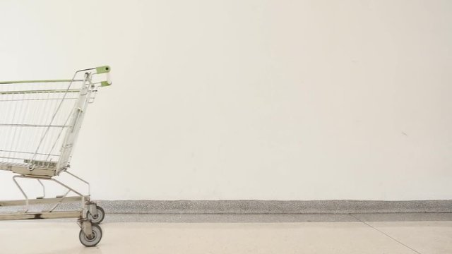 Pushing an empty shopping cart on white background