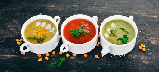 Set of hot, colored vegetable soups. Broccoli soup, corn, tomato soup. Healthy food. On a black...