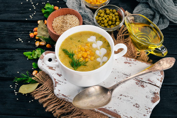 Corn soup with fresh vegetables in a bowl. Healthy food. On a black wooden background. Top view. Copy space for your text.