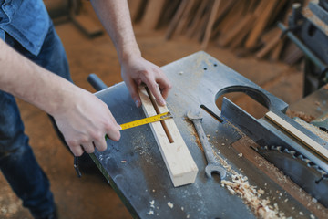 Carpenter with ruler measuring wood plank at workshop