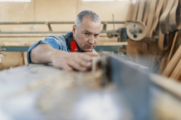 A carpenter works on woodworking the machine tool. Carpenter working on woodworking machines in carpentry shop.