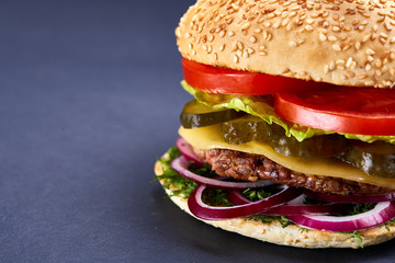 Classic American cheeseburger with black flag on the top over dark background, close-up, selective focus