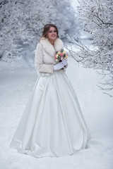 Fototapeta na wymiar Bride in a white fur coat on a snow-covered street