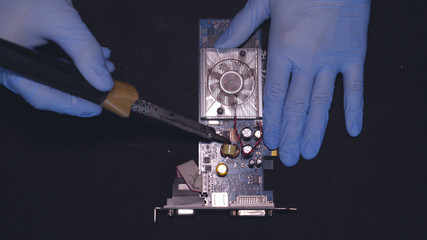 Master in blue rubber gloves, repairing the board, chip, cleaning the video card, soldering a spot,...