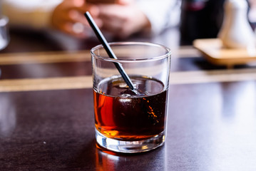 Glass of cola with whiskey on restaurant table