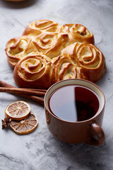 Homemade rose bread, cup of tea, dried citrus and spicies on white textured background, close-up, shallow depth of field