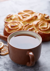 Homemade rose bread, cup of tea, dried citrus and spicies on white textured background, close-up, shallow depth of field