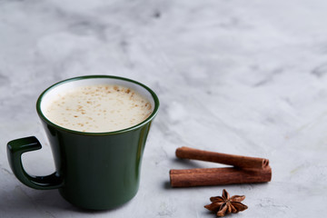 Cup of creamy coffee with cinnamon and star anise on a white textured background, top view, close-up, selective focus