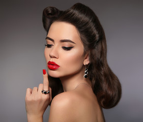 Beauty makeup. Fashion women jewelry. Retro woman portrait with red lips make-up and curly pinup hair style isolated on gray background. Pin up girl.