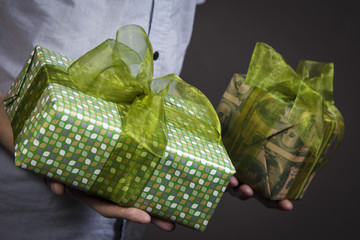The guy holds two boxes with gifts and green bows