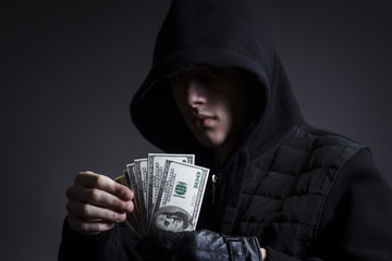 The swindler in the hood counts the stolen money - obrazy, fototapety, plakaty