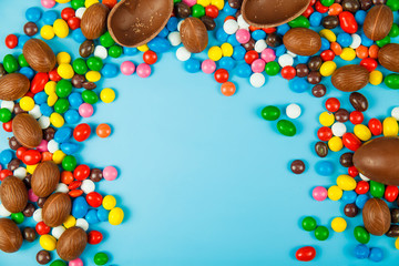 Chocolate eggs and glaze color candy on blue background