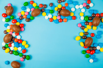 Chocolate eggs and glaze color candy on blue background