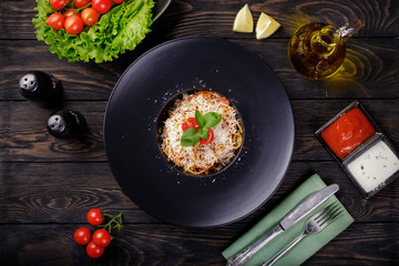 Spaghetti bolognese on black plate.