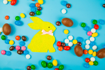 Chocolate eggs and glaze color candy on blue background