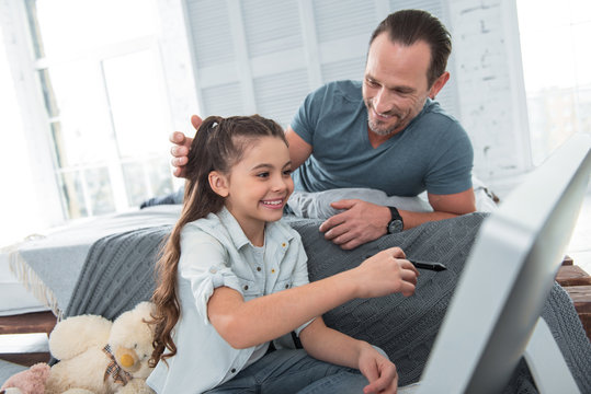 Caring father. Nice positive joyful man looking at his daughter and smiling while spending time with her